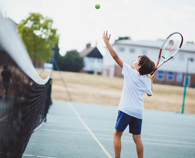 Jovem a jogar ténis num campo ao ar livre, como parte das atividades do curso intensivo de ingles em londres