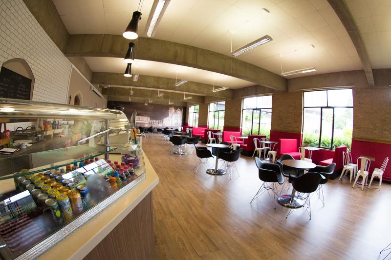 Cantina moderna e espaçosa com mesas e áreas de descanso para estudantes em curso de lingua inglesa.