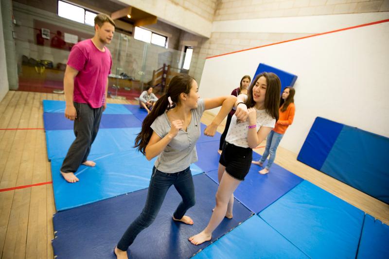 Grupo de jovens a jogar desportos em campo ao ar livre, como parte das atividades de um curso de lingua inglesa.