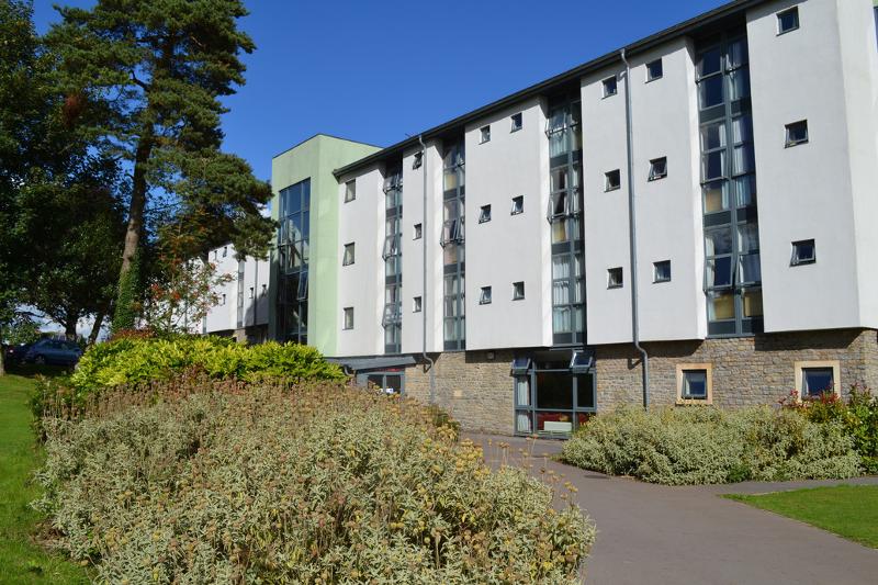 Residência estudantil moderna rodeada de espaços verdes, destinada a estudantes de curso de lingua inglesa.