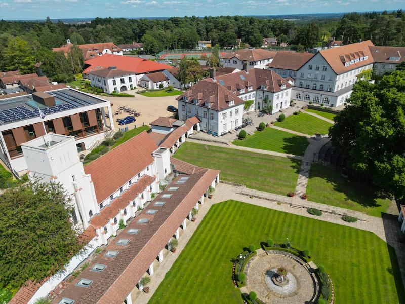 Vista aérea de um campus rodeado por áreas verdes e edifícios de arquitetura diversificada, ideal para um ambiente de aprendizado.