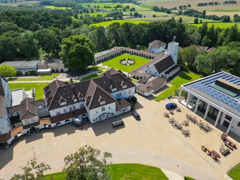 Vista aérea de um campus rodeado pela natureza, com edifícios variados e um bonito jardim, ideal para o teu curso de lingua inglesa.