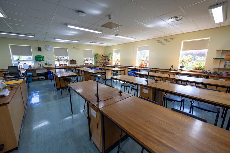 Sala de aula bem iluminada e organizada, perfeita para o teu curso de lingua inglesa, equipada com mesas de trabalho e recursos didáticos.
