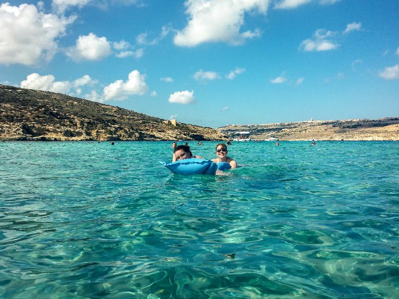 Dois jovens a relaxar nas águas cristalinas durante um curso de ingles em malta, aproveitando um momento de lazer.