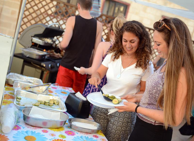 Jovens a servir-se num churrasco ao ar livre durante um curso de ingles em malta, aproveitando um momento de convivência.
