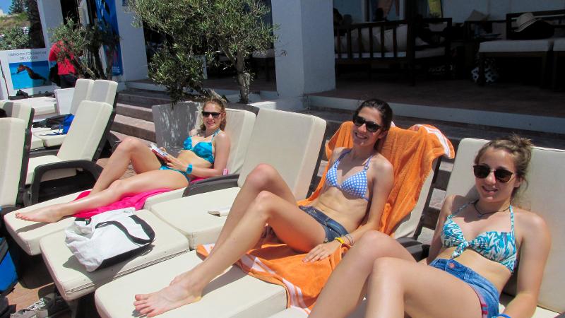 Jovens a relaxar em espreguiçadeiras ao sol durante uma pausa num curso de ingles em malta, aproveitando o clima mediterrâneo.