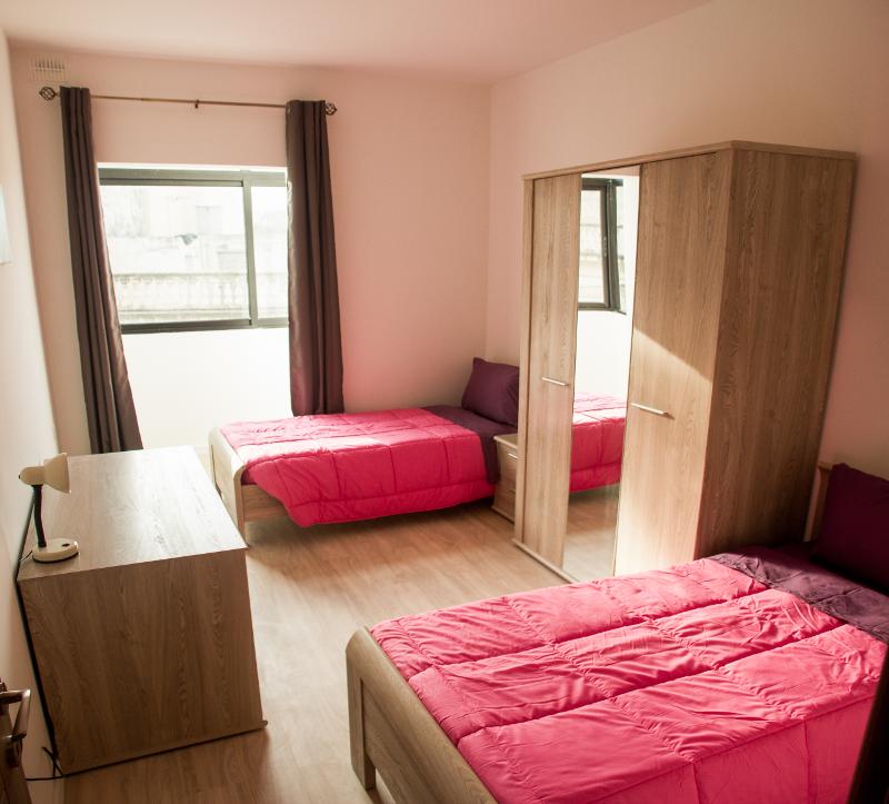 Quarto luminoso e confortável com duas camas individuais, destinado a estudantes de um curso de ingles em malta.