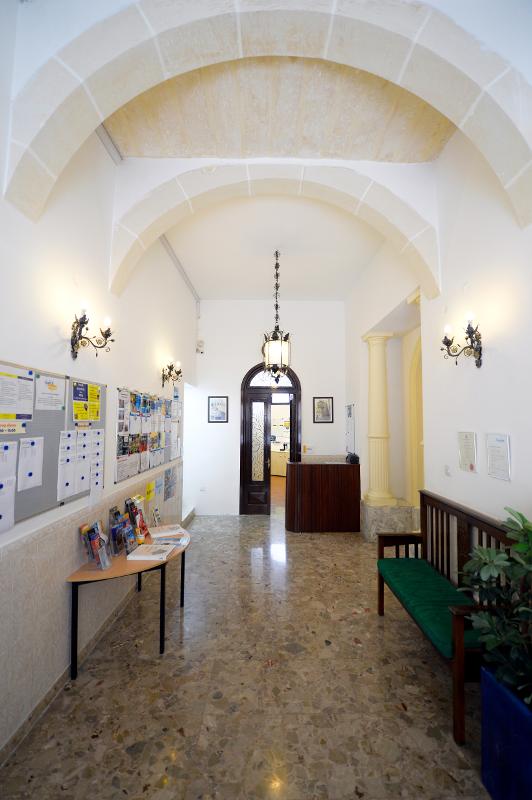Entrada de uma escola com um teto abobadado e murais informativos, parte de um curso de linguas em malta, oferecendo um ambiente acolhedor.