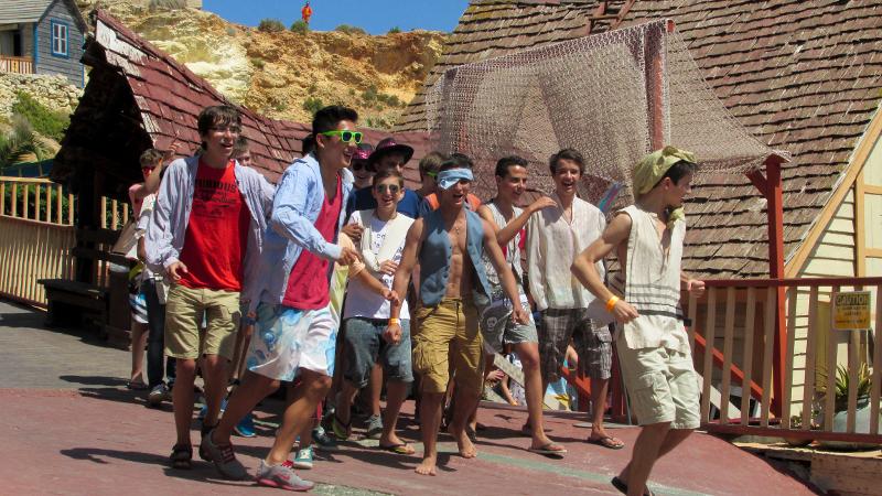 Grupo de jovens a participar numa atividade temática ao ar livre durante um curso de linguas em malta, vestidos de forma divertida e casual.