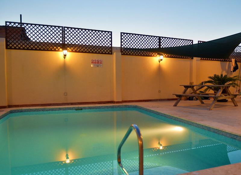 Piscina iluminada ao entardecer em um espaço exterior, oferecendo relaxamento para os estudantes de um curso de linguas em malta.
