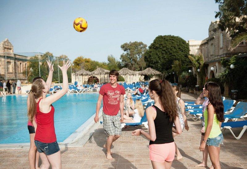 Grupo de estudantes a jogar bola à beira da piscina, desfrutando de um ambiente descontraído durante um curso de linguas na alemanha