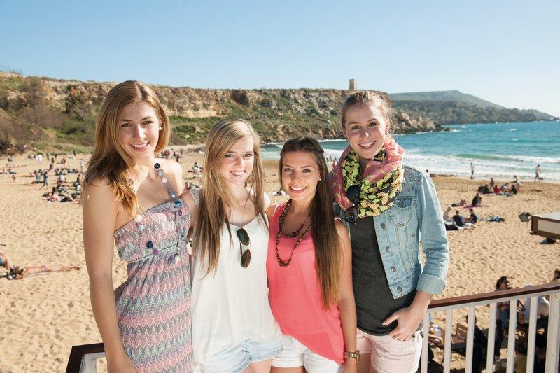 Grupo de estudantes a posar na praia com vista para o mar, um local perfeito para socializar e relaxar durante um curso de linguas na alemanha.