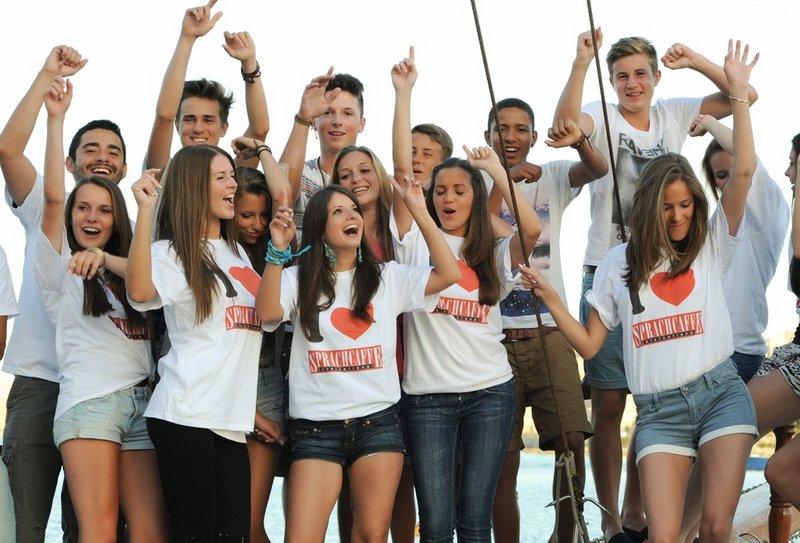Grupo de jovens do curso de ingles na alemanha, sorrindo durante uma atividade em grupo, usando blusas com o logotipo de "Sprachcaffe".