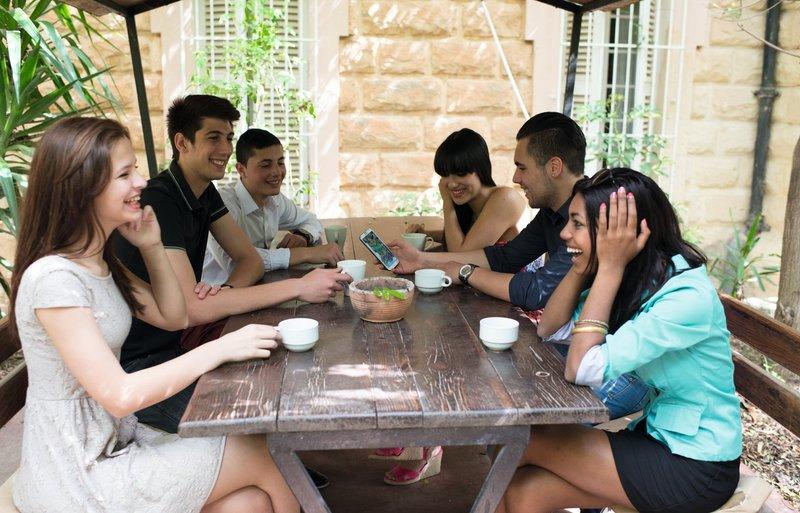 Grupo de jovens a socializar numa área exterior, enquanto desfrutam de bebidas durante o seu curso de linguas na alemanha. Ambiente relaxado e acolhedor.