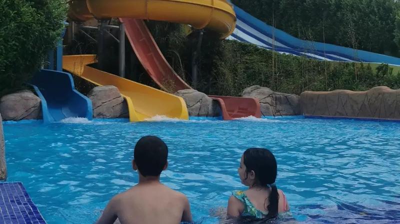 uma menina e um menino sentados na piscina a conversar no campo de férias Vila Real