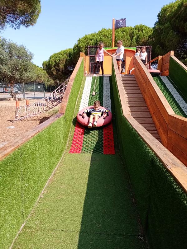 menino pequeno a descer um escorrega sentado numa bóia no campo de férias Vila Real