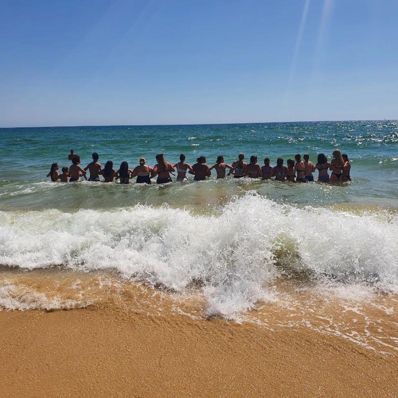 fotografia de grupo agarrados uns aos outros dentro do mar no surf camp algarve