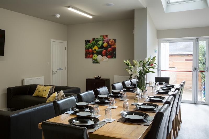 Sala de refeições elegante com mesa grande preparada para refeições, parte do curso de ingles cambridge, ideal para socialização.