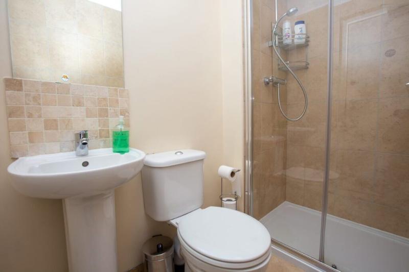 Casa de banho moderna com lavatório, sanita e chuveiro, disponível para participantes do curso de língua inglesa, proporcionando conforto e conveniência.