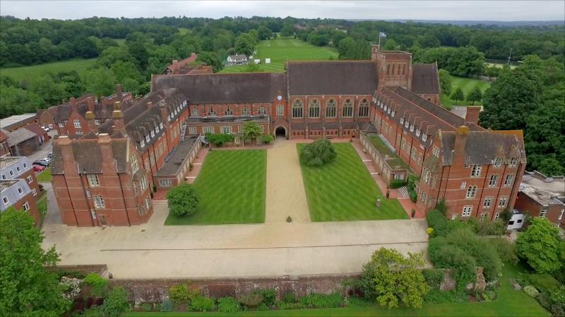 Vista aérea de um impressionante edifício de tijolos rodeado de jardins verdes, onde se realiza um curso de inglês no estrangeiro.