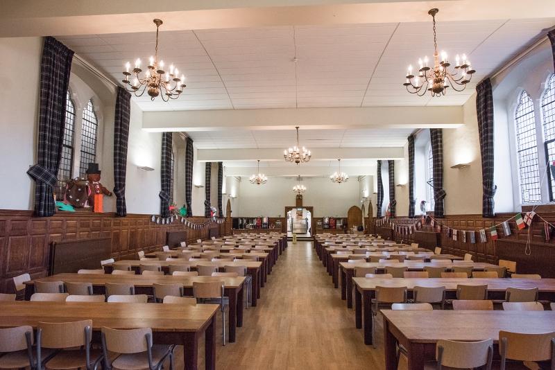 Cantina rústica e grande com mesas e cadeiras de madeira, durante o curso de inglês no estrangeiro.