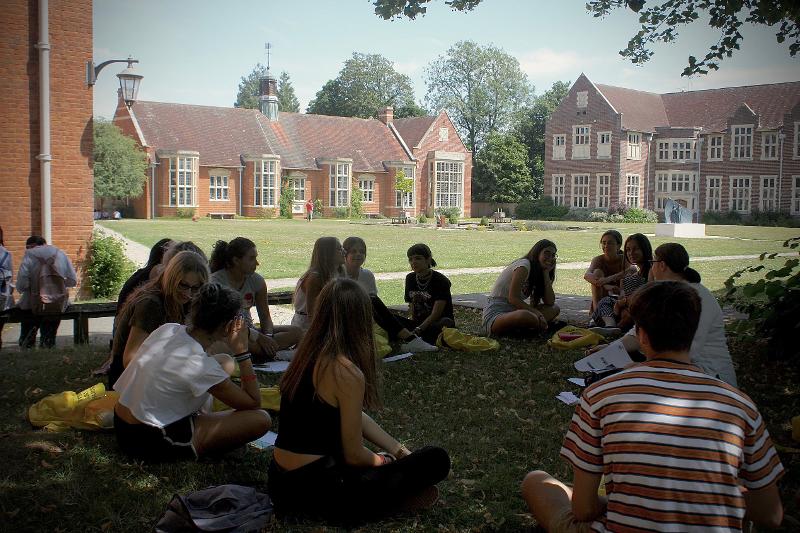 Grupo de estudantes sentados ao ar livre, em círculo, a participar numa aula do curso de inglês em londres 4 semanas.