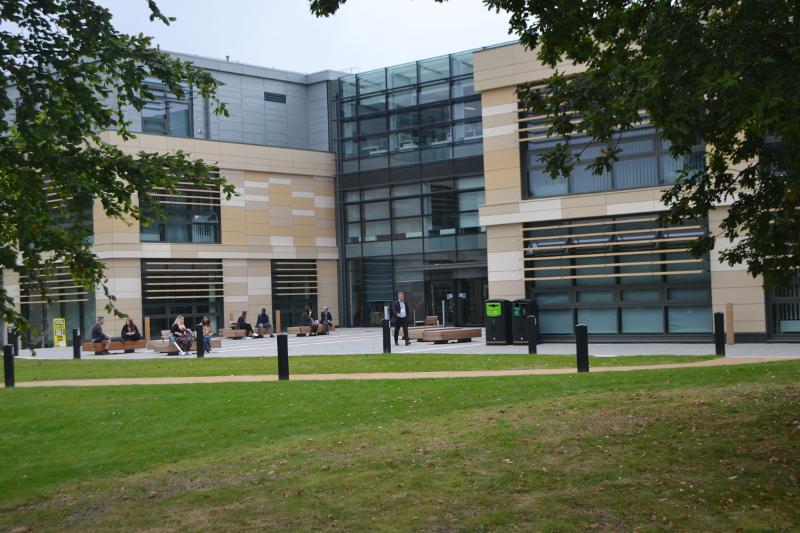 Edifício moderno com fachada de vidro, rodeado por áreas verdes, criando um ambiente agradável para um curso de língua inglesa.