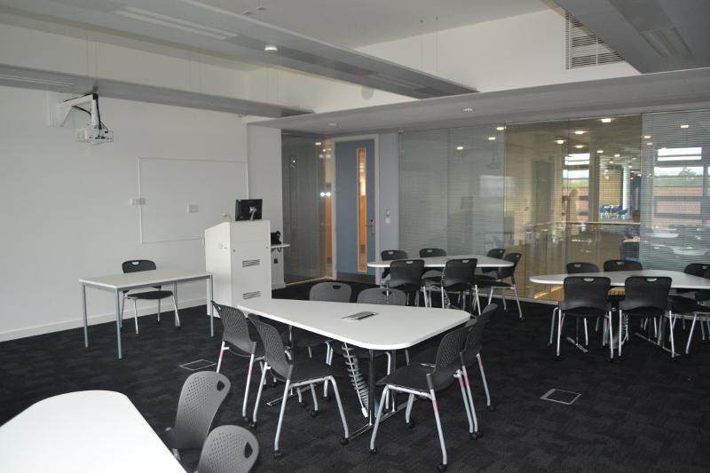 Sala de aula moderna e equipada com mesas e cadeiras, ideal para sessões interativas num curso de língua inglesa.