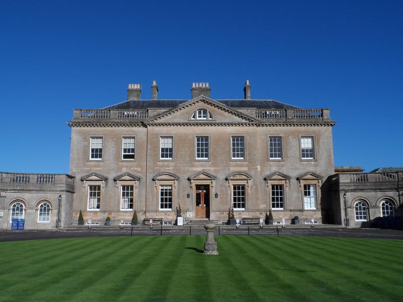 Edifício clássico com fachada simétrica e relvado cuidado, proporcionando um ambiente elegante para um curso de língua inglesa.