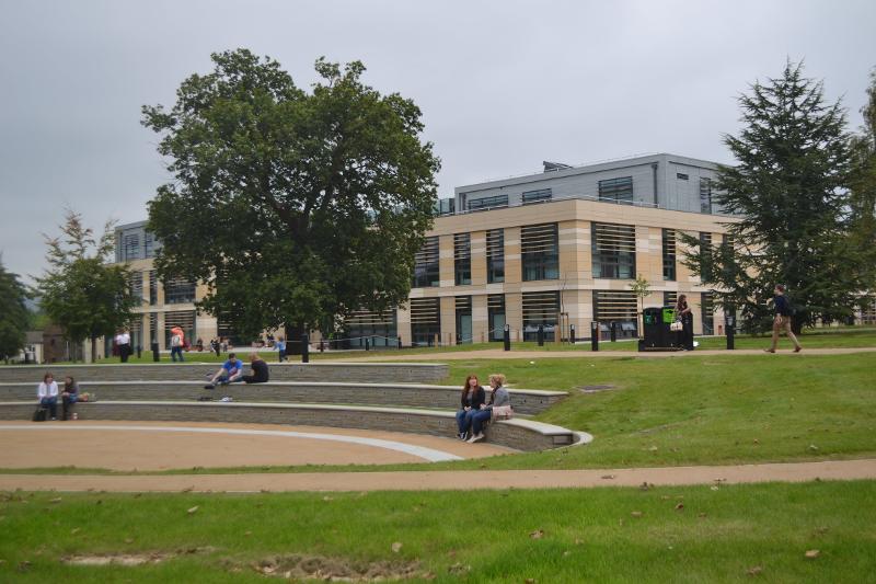 Área externa com jardim ao ar livre, à frente de um edifício moderno, ideal para momentos de descontração durante um curso de língua inglesa.