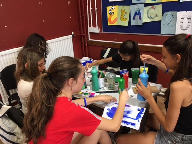 Grupo de estudantes a pintar e a criar trabalhos artísticos como parte das atividades de um curso de língua inglesa.