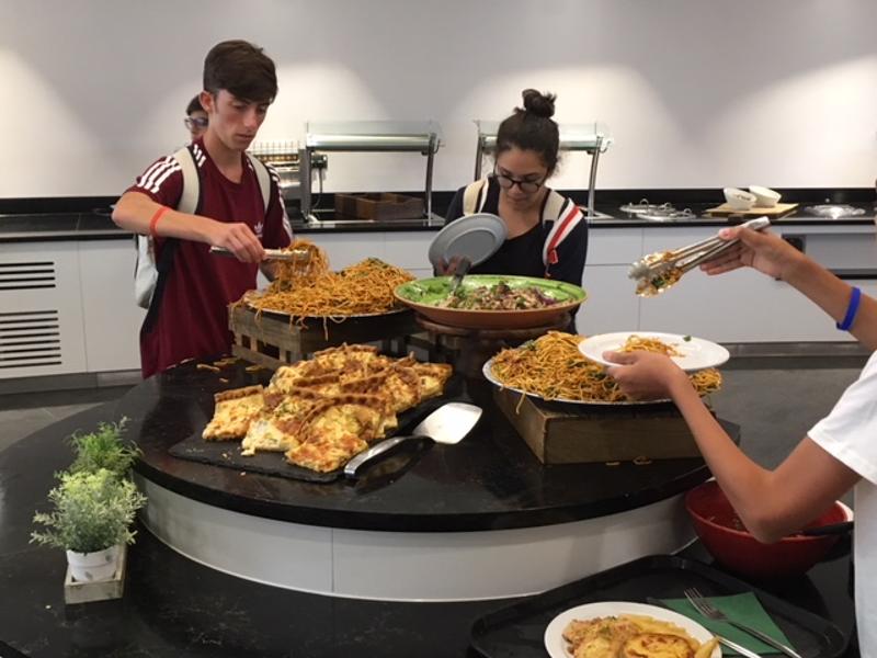 Estudantes a servir-se num buffet variado, aproveitando uma refeição durante o curso de língua inglesa.