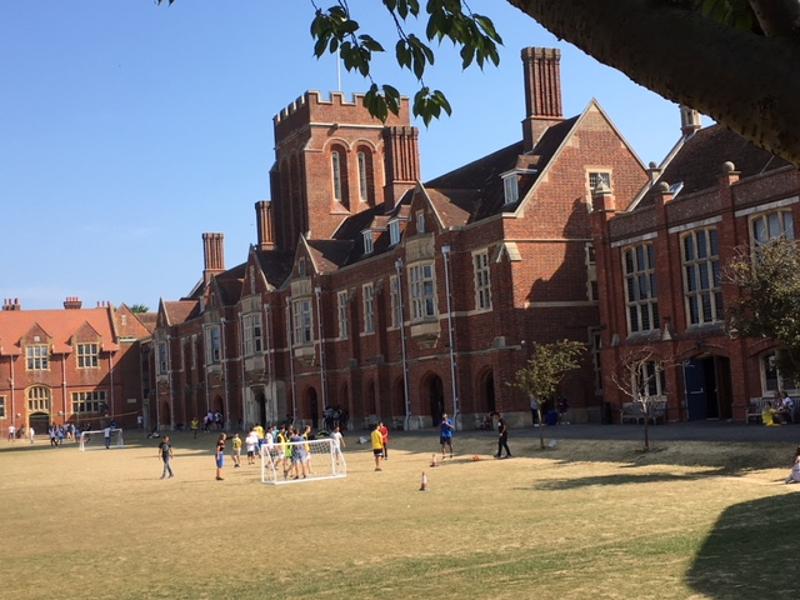  Estudantes a jogar futebol num campo em frente a um edifício histórico, desfrutando de atividades ao ar livre durante o curso de língua inglesa.