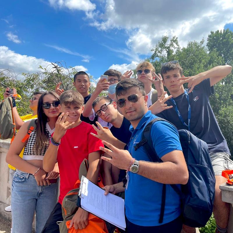 Grupo de estudantes a posar animadamente para uma foto ao ar livre durante o curso de língua inglesa.