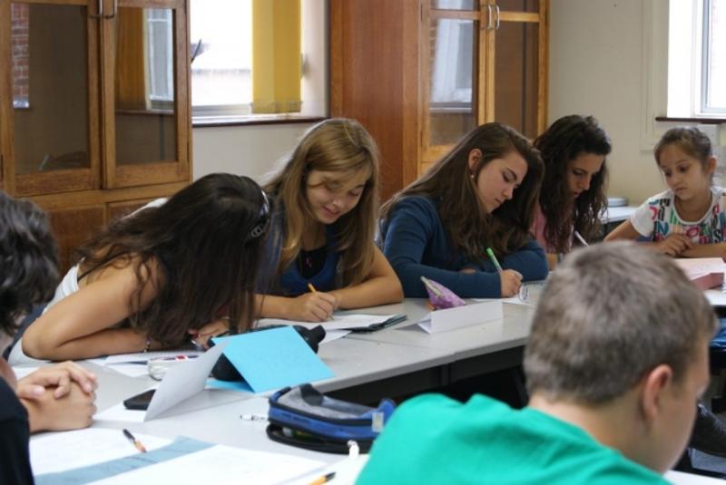 Alunos participando num curso de inglês no Reino Unido, concentrados em atividades de escrita em sala de aula.