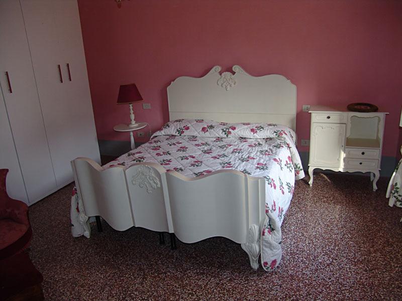Quarto acolhedor com cama de estilo clássico, decorado com uma colcha floral, ideal para descansar durante o curso italiano.