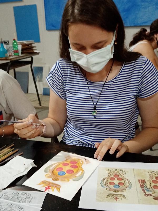 Participante a pintar e a criar arte durante uma atividade cultural num curso italiano.