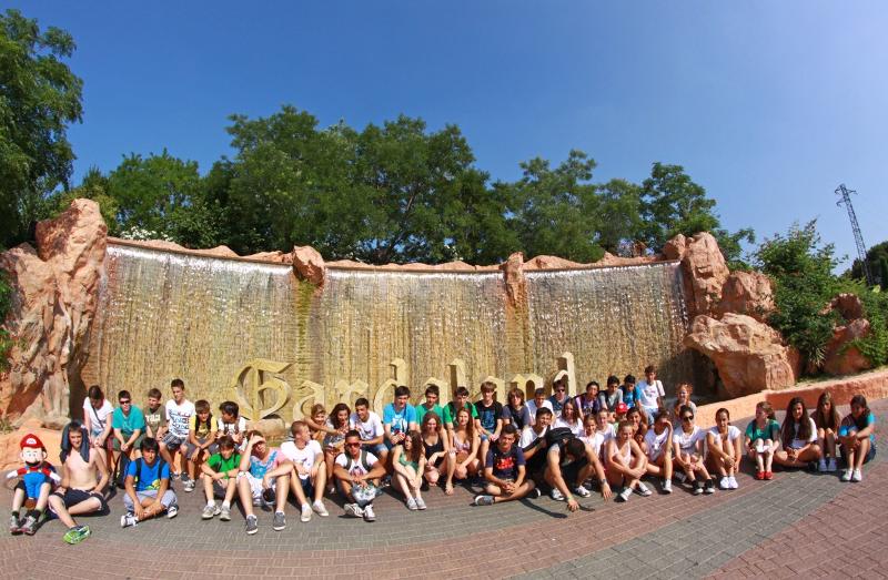 Grupo de estudantes reunidos em frente a uma cascata no parque Gardaland durante um curso italiano.