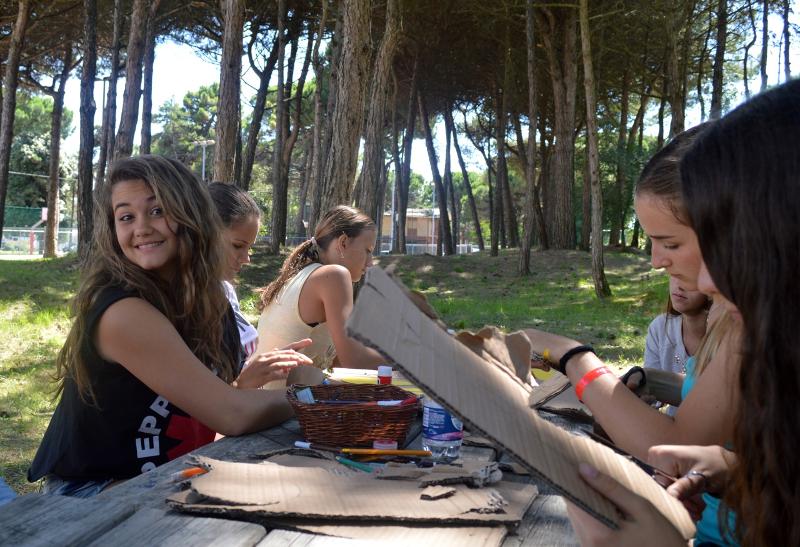 Grupo de jovens a fazer atividades de artesanato ao ar livre, enquanto participam num curso italiano.