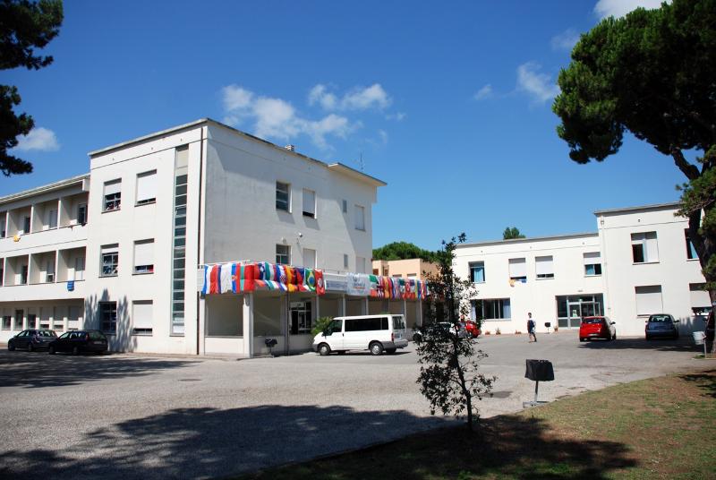 Edifício escolar com várias bandeiras expostas, representando diferentes países, onde se realiza o curso italiano.