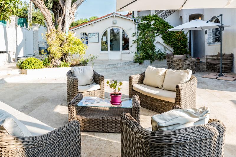 Pátio acolhedor ao ar livre com móveis de vime e jardim, perfeito para relaxar durante um curso de língua francesa