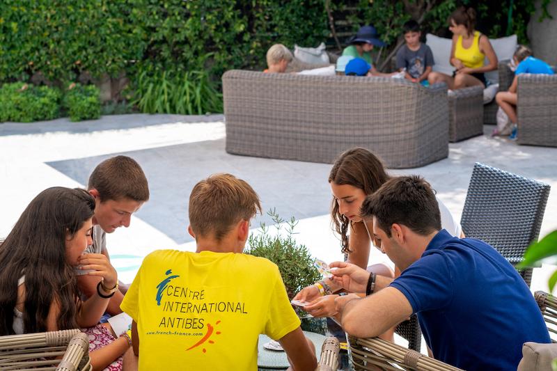 Grupo de jovens a trabalhar juntos em atividades ao ar livre, com um instrutor do Centre International d'Antibes ao lado