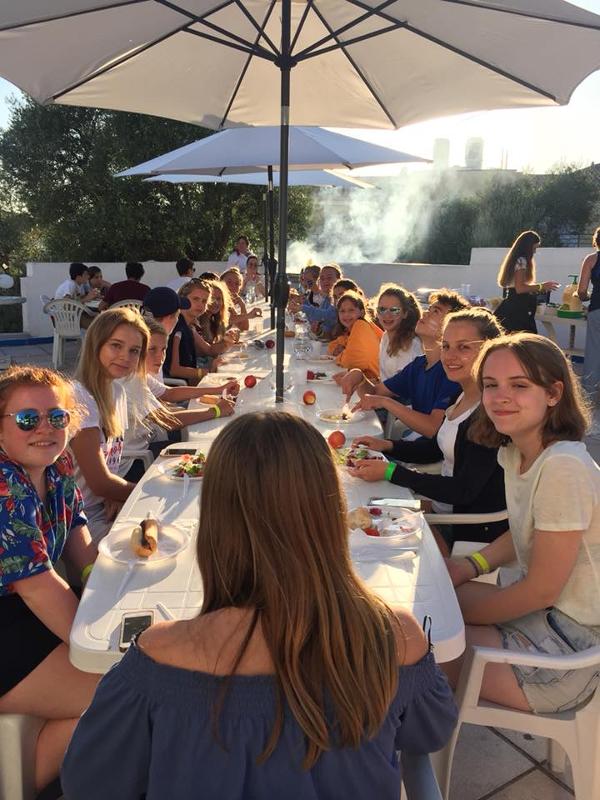 Participantes a comer todos juntos numa mesa corrida durante o curso de línguas 