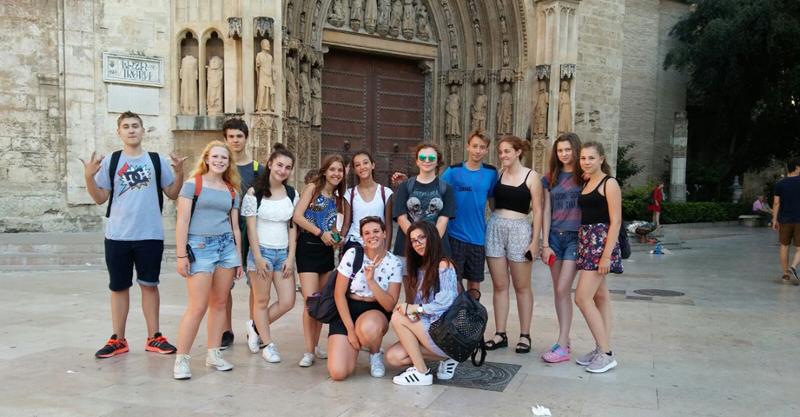 Grupo de jovens posa em frente a um monumento histórico como parte de uma excursão cultural de um curso de espanhol.