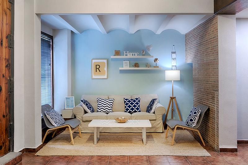 Sala de estar acolhedora com sofá, cadeiras confortáveis e decoração moderna, usada por estudantes de um curso de espanhol para relaxar.