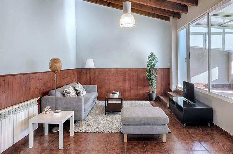Sala de estar confortável com sofá, mesa de centro e televisão, proporcionando um espaço de descanso para estudantes de um curso de espanhol.