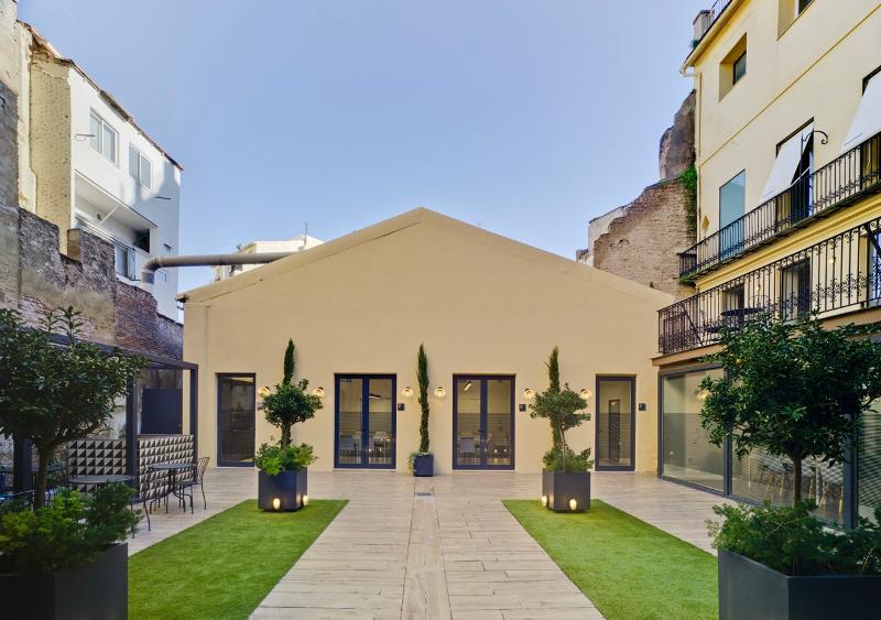 Pátio ao ar livre com plantas e edifícios ao redor, usado para atividades e encontros durante um curso de espanhol.