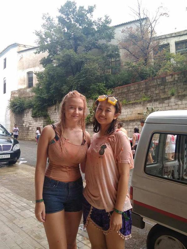 Duas jovens com roupas molhadas e sorridentes após participarem numa atividade divertida ao ar livre durante um curso de espanhol.