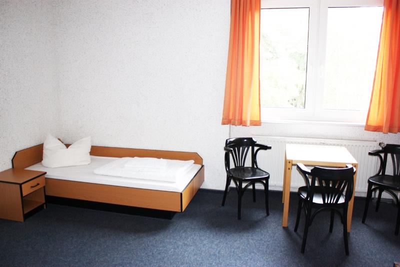 Quarto simples com cama de solteiro e janela, ideal para quem procura conforto durante um curso de inglês na alemanha.