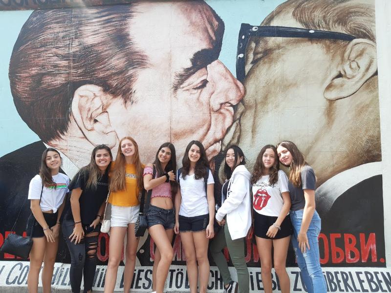 Grupo de raparigas em frente ao Muro de Berlim, explorando a história enquanto fazem o seu curso de inglês na alemanha.